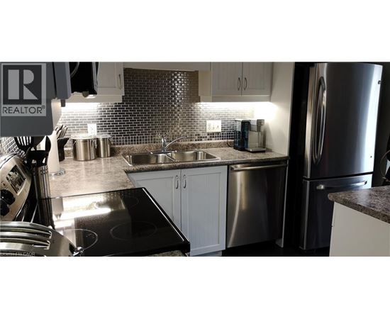A kitchen with a stove top oven, sink, and refrigerator.