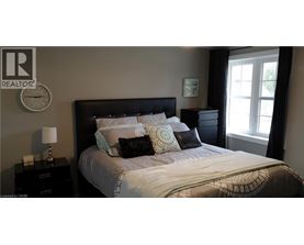 A bedroom with a large bed and a window with curtains.