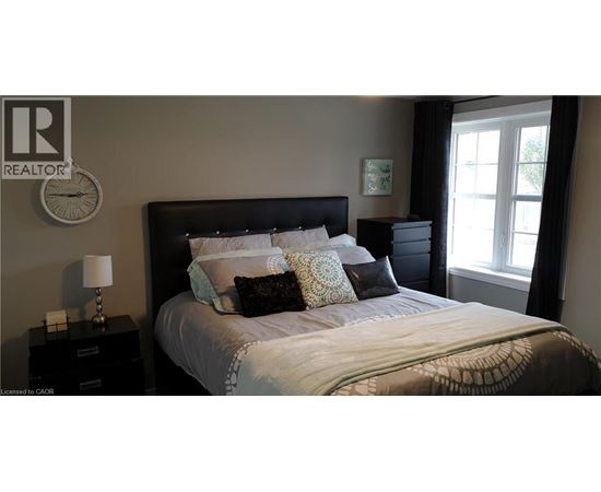 A bedroom with a large bed and a window with curtains.