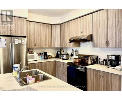 A kitchen with wooden cabinets and a stainless steel refrigerator.