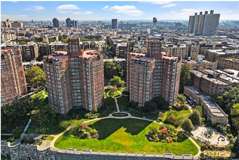 A cityscape with a large park in the foreground and buildings in the background.