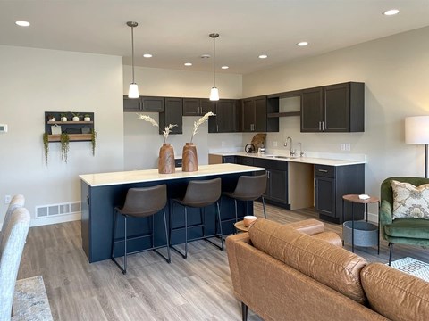 A modern kitchen with a bar area and a brown sofa.