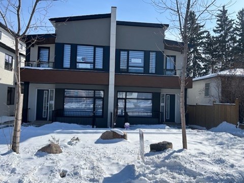 A modern house with a large front yard covered in snow.