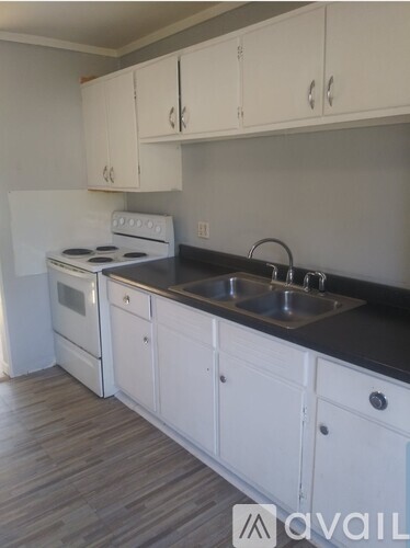 A kitchen with white cabinets and a black countertop.