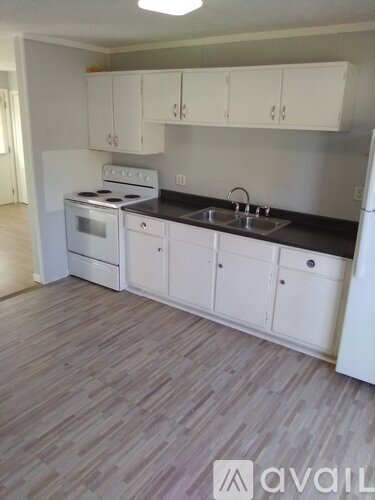 A kitchen with white cabinets and a black countertop.
