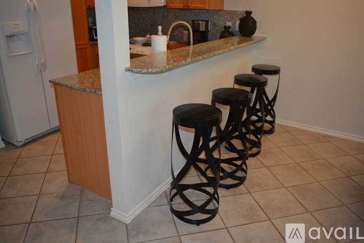 A kitchen with a white refrigerator and a counter with a sink and a white pitcher on it.