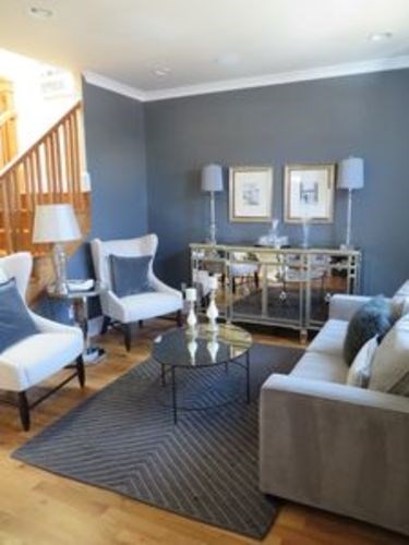A living room with a grey couch, a coffee table, and a glass table with a metal frame.