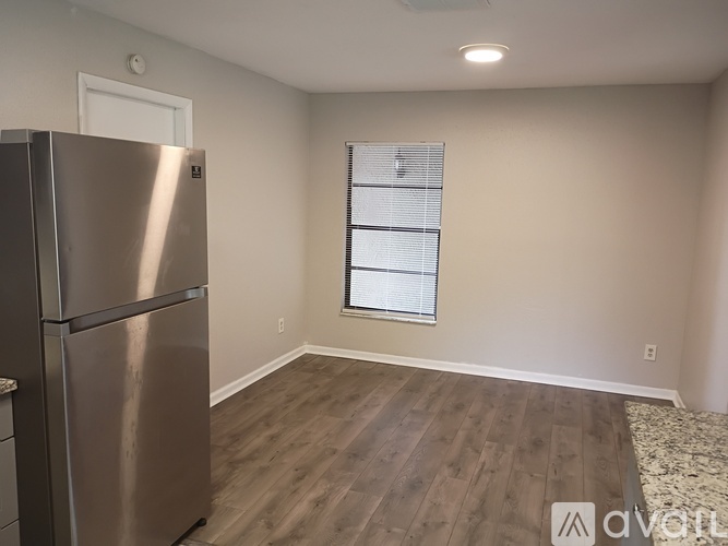 A kitchen with a stainless steel refrigerator and wooden flooring.