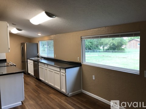 A kitchen with white cabinets and a black countertop.