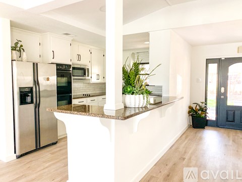 A kitchen with a refrigerator, microwave, oven, and a counter with a plant on it.