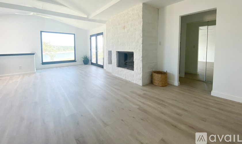 A spacious living room with a fireplace and a large window.