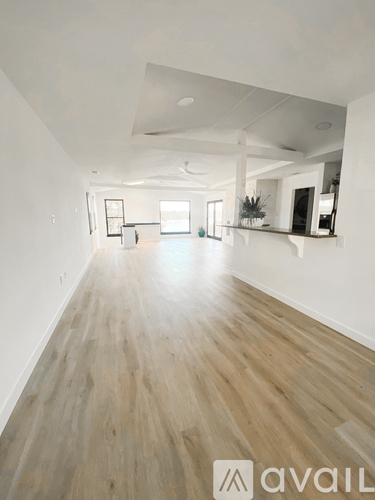 A spacious room with wooden flooring and white walls.