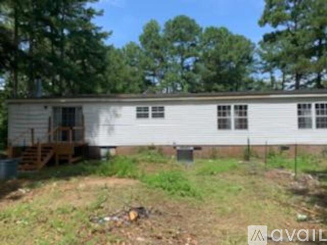 A white mobile home with a porch and a tree in the background.
