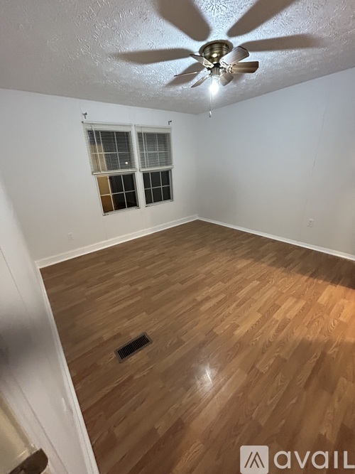 A room with a ceiling fan and wooden flooring.