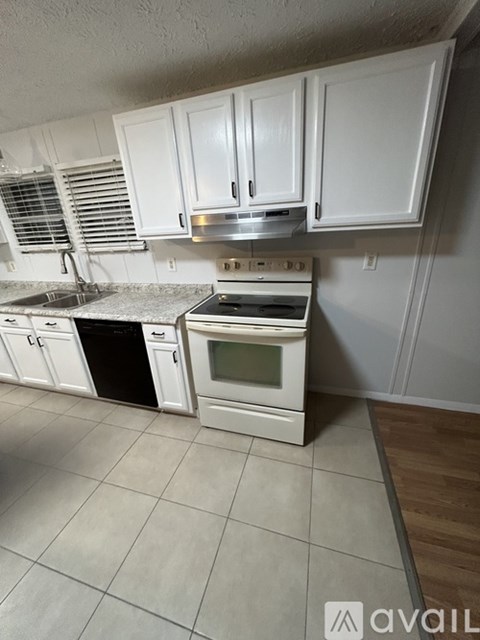 A kitchen with white cabinets and appliances.