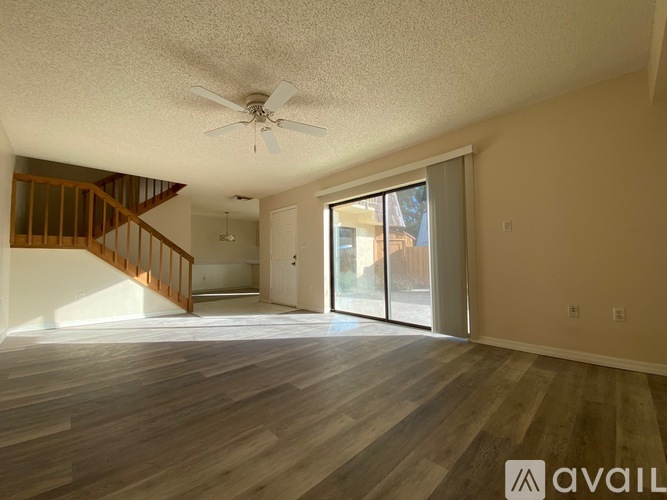 A spacious room with wooden flooring and a ceiling fan.
