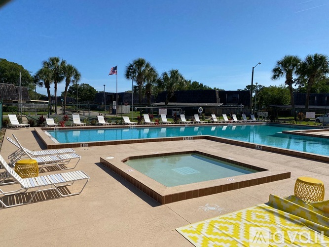 A pool area with a hot tub and lounge chairs.