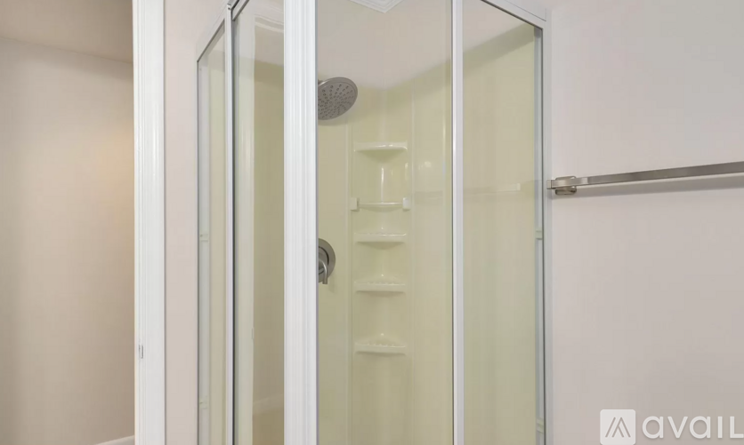 A shower with a glass door and a white wall.