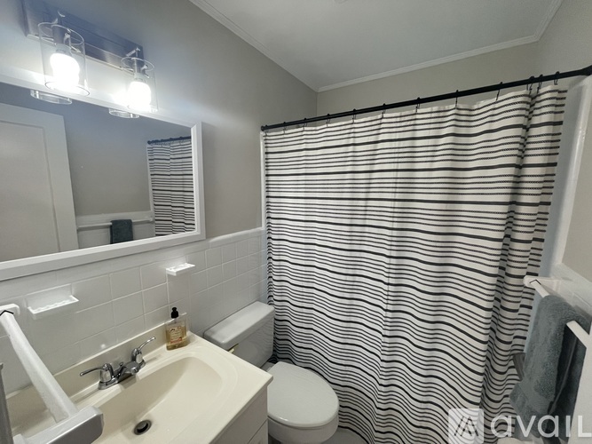 A bathroom with a white sink, toilet, and striped shower curtain.