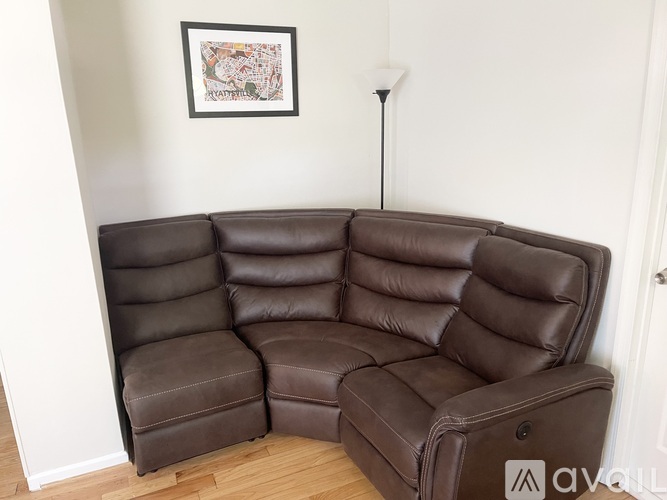 A brown leather sofa in a room with a picture on the wall.