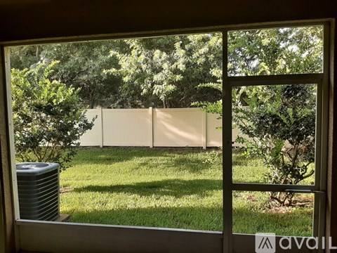 A window with a view of a green lawn and trees.