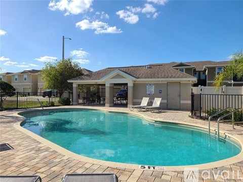 A swimming pool surrounded by a black fence and chairs.