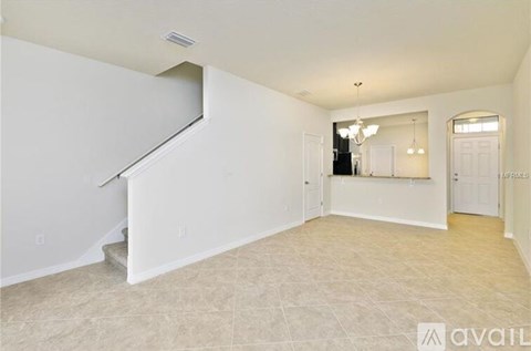A spacious room with a staircase and a chandelier.