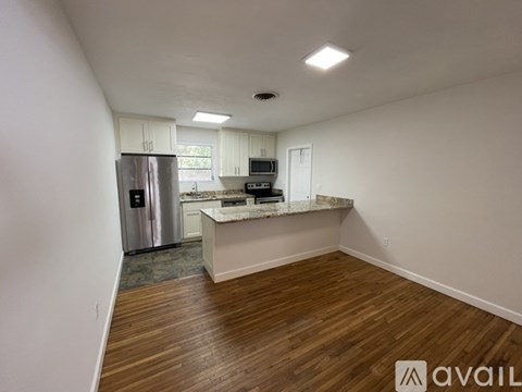 A kitchen with white cabinets and a wooden floor.