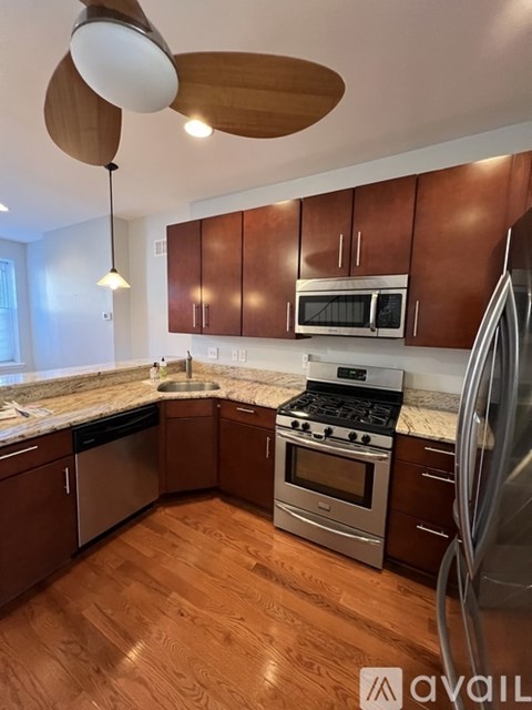 A kitchen with wooden cabinets and a stainless steel refrigerator.