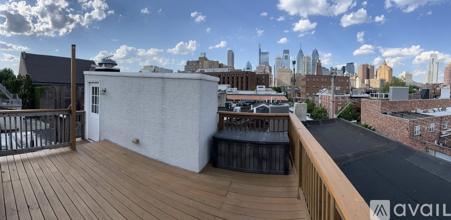 A balcony with a wooden floor and a white wall overlooking a city skyline.