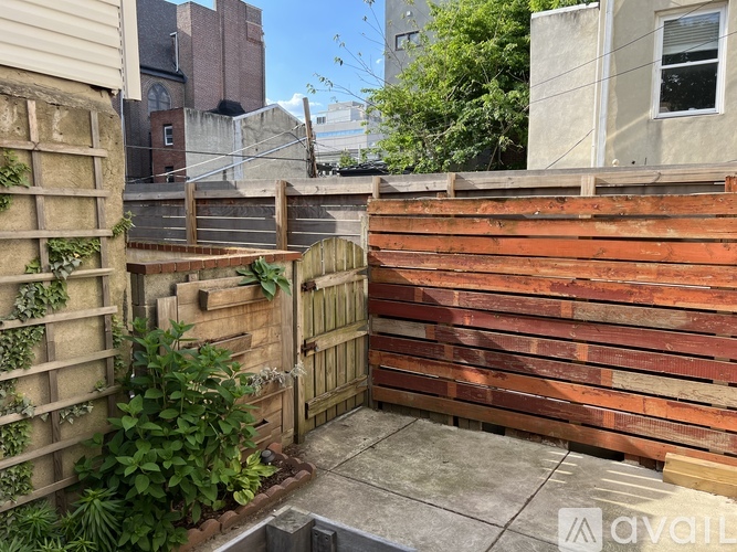 A wooden fence with a gate and plants on the left side.