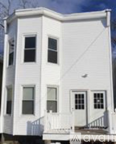 A white two story house with a balcony on the second floor.
