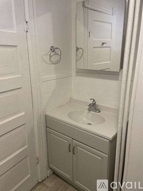 A white bathroom with a sink and a mirror.