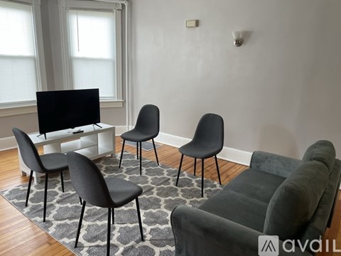A living room with a grey sofa, black chairs and a television.