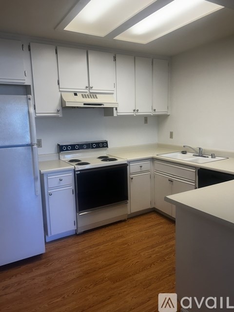 A kitchen with white cabinets and a wooden floor.