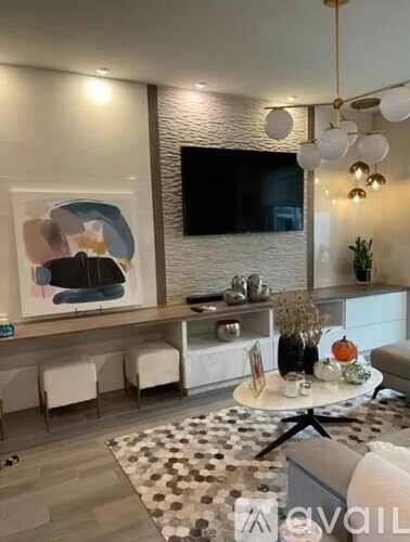 A living room with a large painting on the wall and a TV above the fireplace.