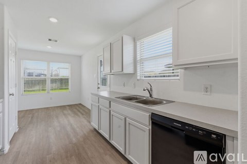 A kitchen with white cabinets and a black dishwasher.