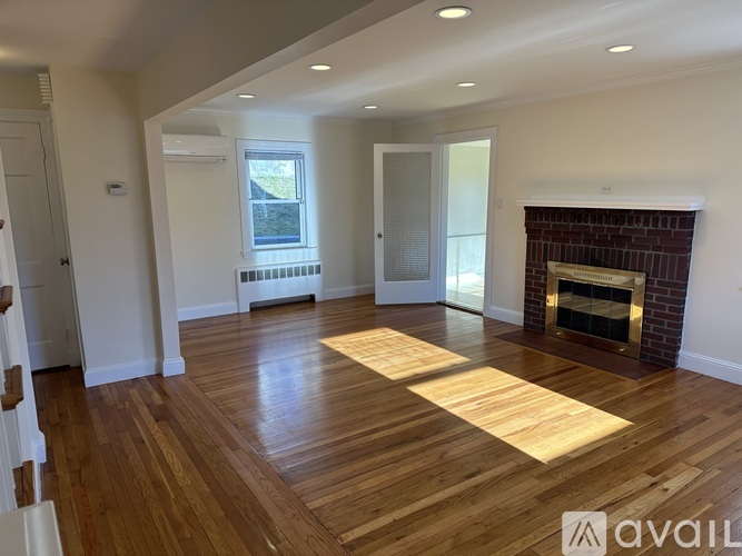 A living room with a fireplace and wooden floors.