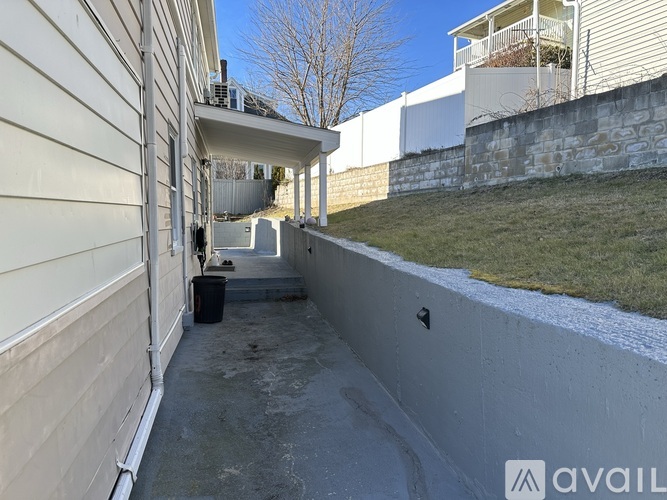 A concrete walkway leads to a building with a balcony.