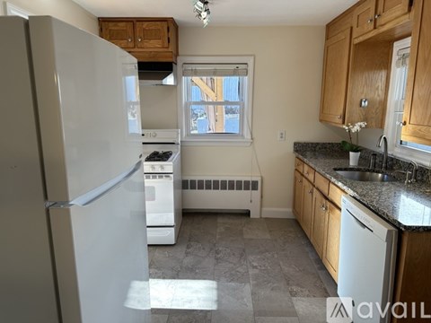 A kitchen with a white refrigerator, a window, and a sink.