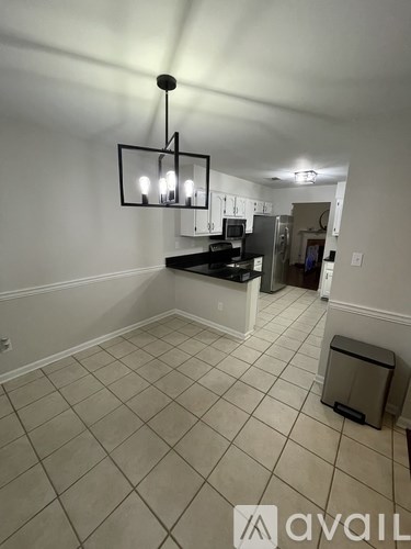 A kitchen area with a black fridge and a black and white chandelier.