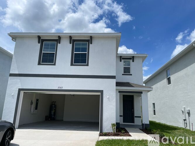 A white two-story house with a garage and a car parked in front.
