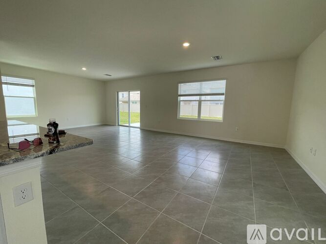 A spacious room with tiled flooring and large windows.