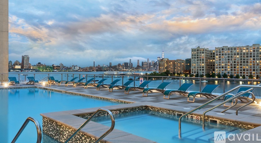 A pool with chairs and a city skyline in the background.