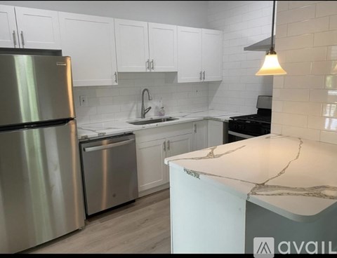 A kitchen with a stainless steel refrigerator and a marble countertop.
