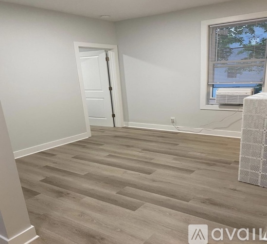 A room with a wooden floor and a door leading to another room.