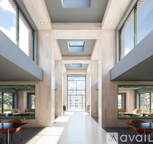 A modern interior space with wooden walls and ceiling, featuring a long hallway with skylights and seating areas on either side.