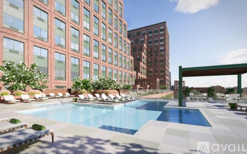 A pool surrounded by lounge chairs and umbrellas in front of a red building.
