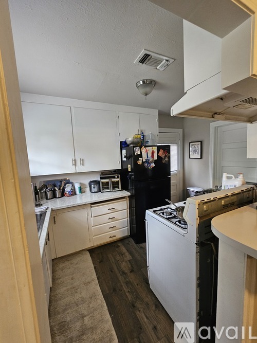 A kitchen with a black fridge and white cabinets.