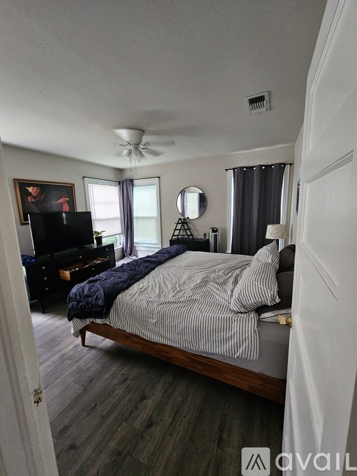 A bedroom with a bed, dresser, and television.